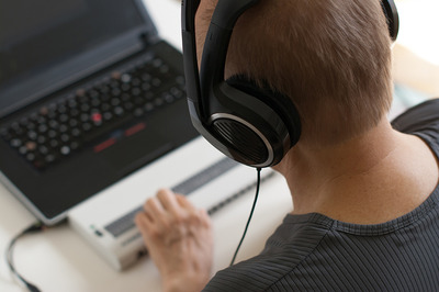 Ein blinder Mann bedient seinen Laptop mit einem ScreenReader (Bildschirm-Leser) und einer Braillezeile (Computerausgabegerät für Bline).