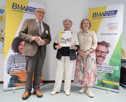 Foto mit 3 Personen, die Person in der Mitte hält eine "80 Jahre BhW" Urkunde.