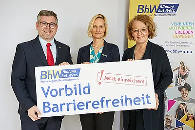 Gruppenbild, Landesrat Ludwig Schleritzko, BhW Geschäftsführerin Therese Reinel und Landesrätin Christiane Teschl-Hofmeister stehen vor einem BhW_Rollup und halten ein Schild hoch, auf dem steht: Vorbild Barrierefreiheit - Jetzt einreichen!