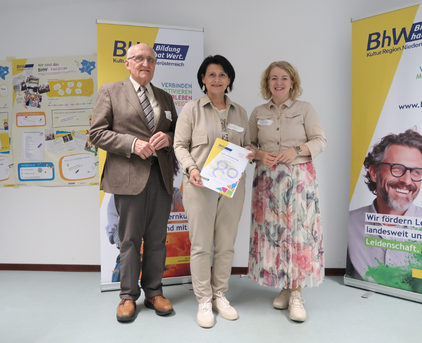 Foto mit 3 Personen, die Person in der Mitte hält eine "80 Jahre BhW" Urkunde.