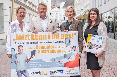 Auf dem Foto sind zu sehen: Geschäftsführerin des Burgenländischen Bildungswerks Judith Tscheppe,  kabelplus-Geschäftsführer Wolfgang Schäffer, Geschäftsführerin des BhW Niederösterreich Therese Reinel und Smartphone-Trainerin Julia Hentschel. Sie alle halten eine Tafel mit der Aufschrift „Jetzt kenn i mi aus! – Für alle, die digital mehr wissen wollen“ zur Bewerbung von gemeinsam durchgeführten Online-Workshops zu Computer- und Smartphone-Themen. 