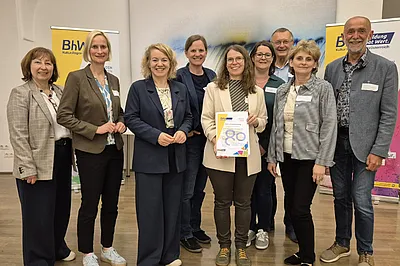 Ein Gruppenbild mit einer Person welche eine "Danke für 80 Jahre" Urkunde bekommen hat.