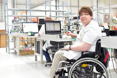Ein Mann im Rollstuhl bei der Arbeit in einem Industriebetrieb.