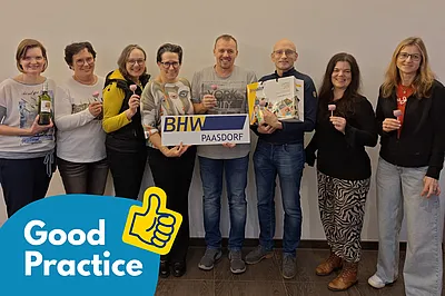 Die Veranstaltenden des Bildungsabends stehen in einem Gruppenbild zusammen und halten eine BHW-Tafel ins Bild. Links unten befindet sich ein blauer Bildkasten mit der Aufschrift "Good Practice"