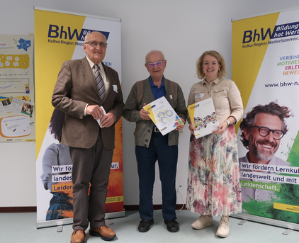 Foto mit 3 Personen, die Person in der Mitte hält eine "80 Jahre BhW" Urkunde.