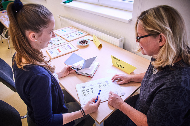 Eine Teilnehmerin der Basisbildung übt, gemeinsam mit einer Lernbeleiterin, das Schreiben.